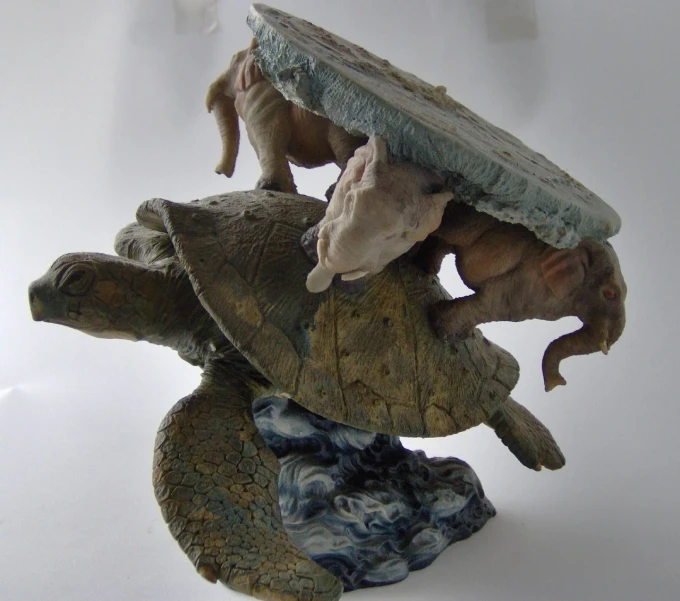 two turtle like sculptures each holding a piece of wood and some clay