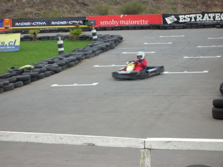 a guy is riding a toy kart in an outdoor race track