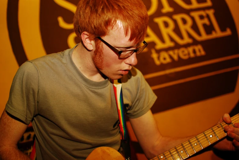 a man with glasses playing a guitar while wearing a tie