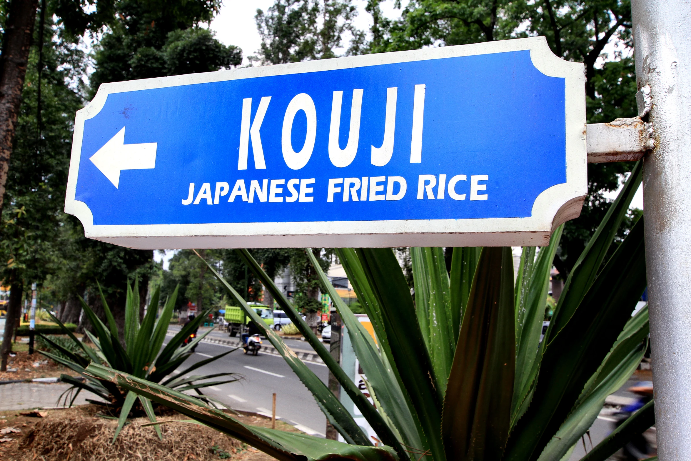 a blue and white sign in front of trees that reads kouji