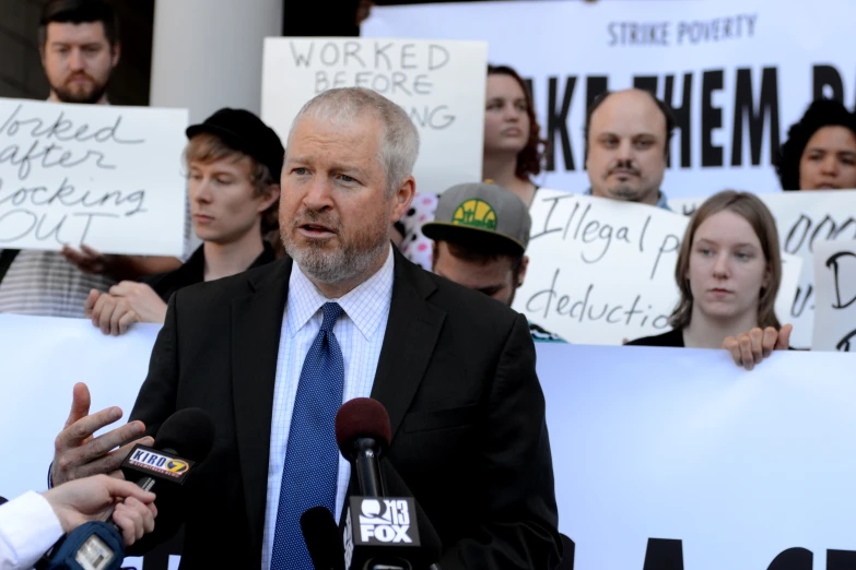 there are many protesters behind this man talking to the press