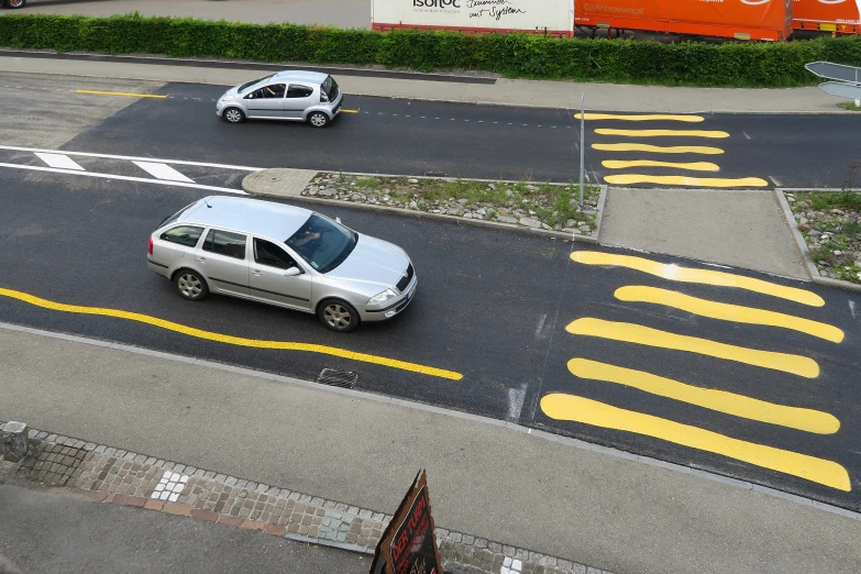 two vehicles driving along a road with yellow painted markings