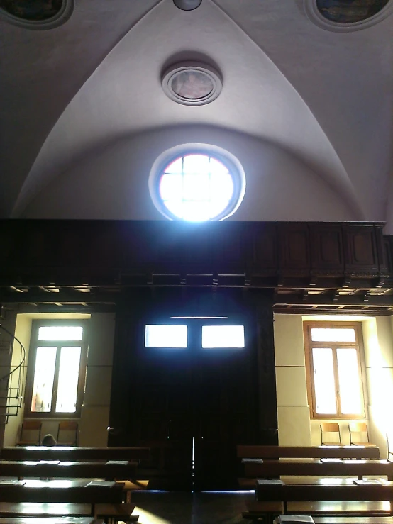 the circular light shines brightly from a high ceiling window in an empty cathedral