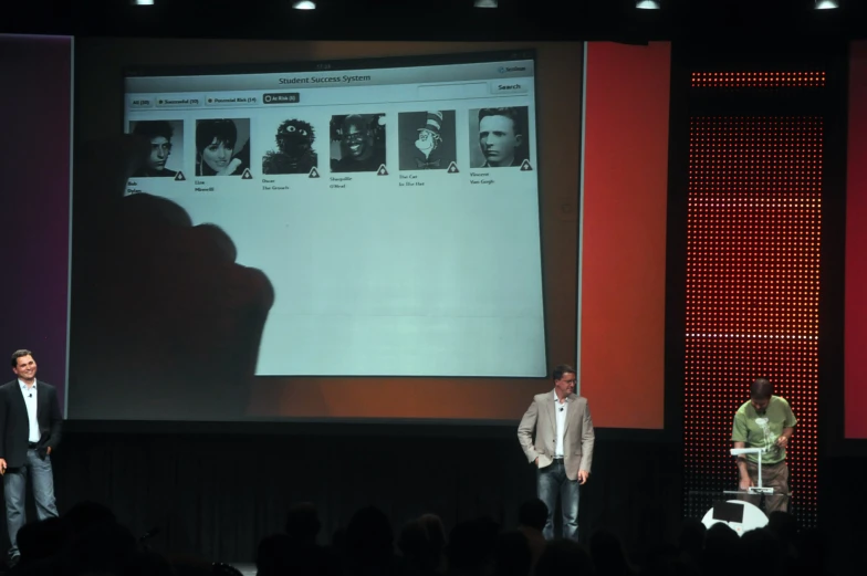 two men at a computer presentation in front of a crowd