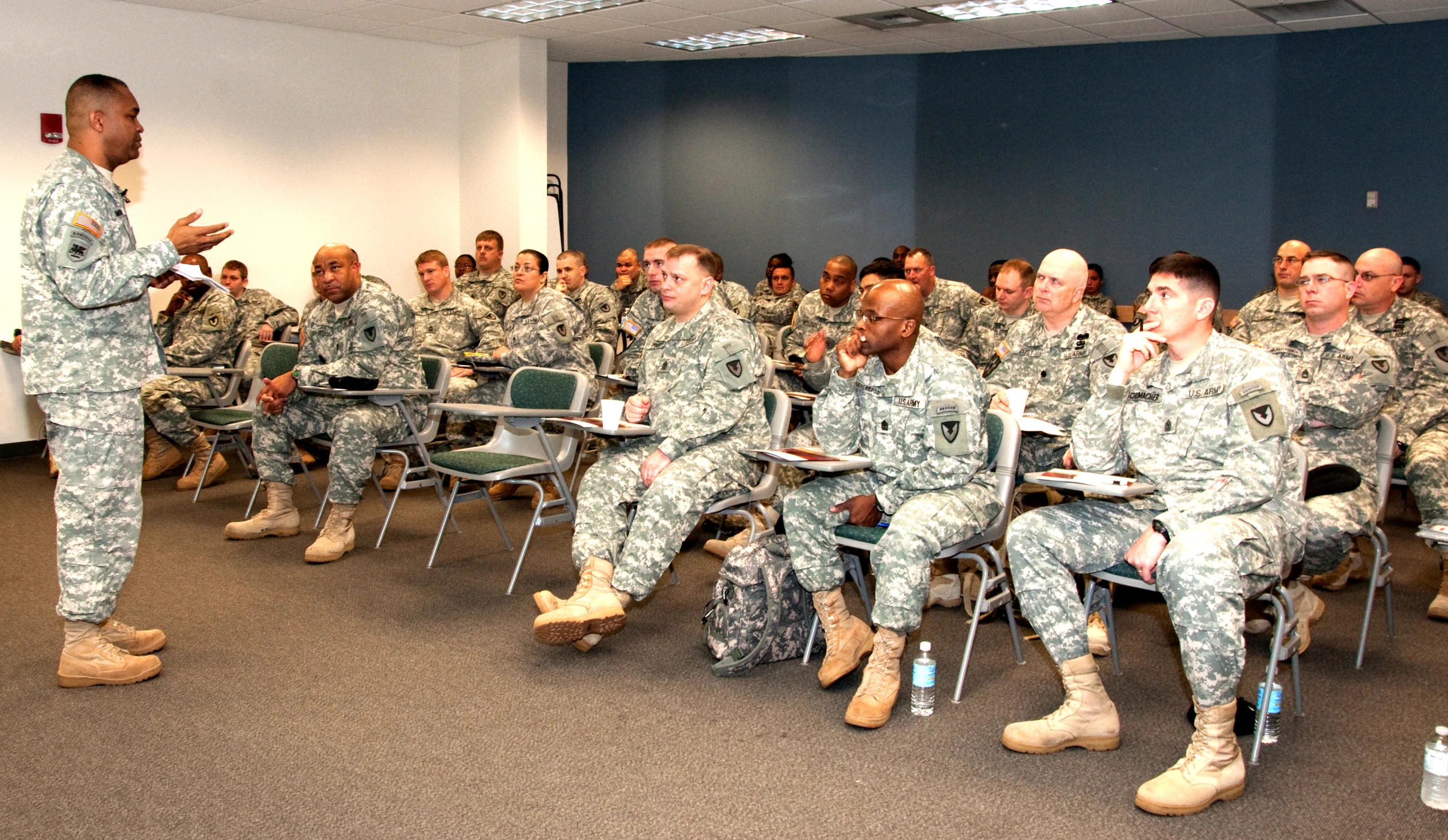 military personnel at their desks listening to the military men