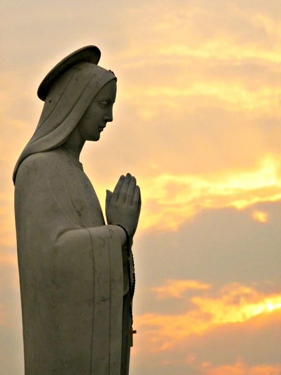 a statue in front of an orange sky