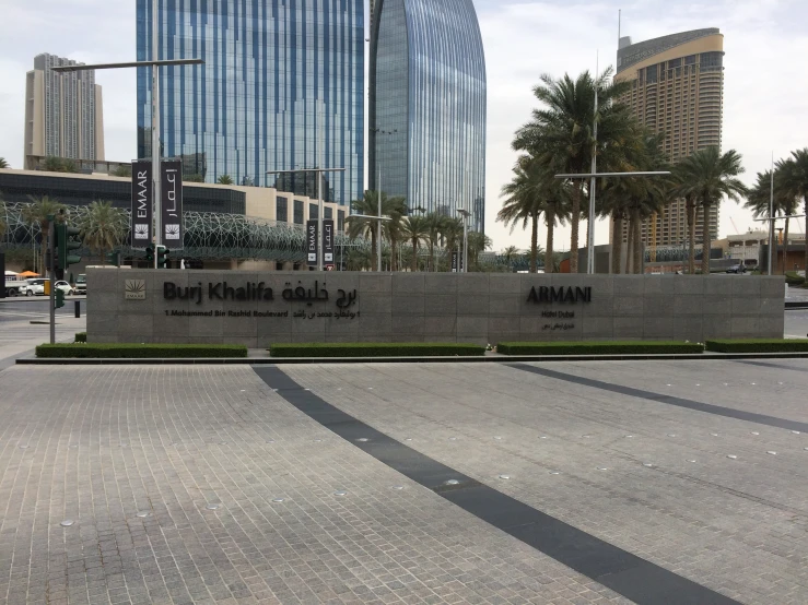 an entrance to the kuwait capital, with a big city building in the background