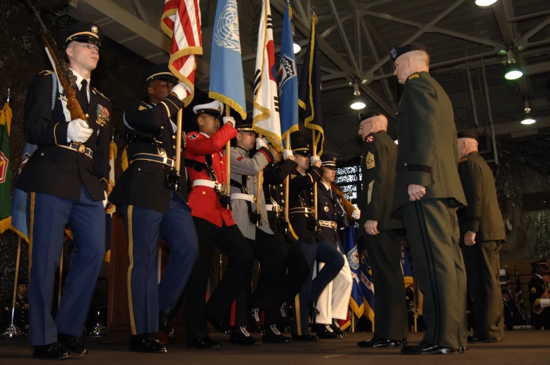 three uniformed men are standing in formation and two of them are talking