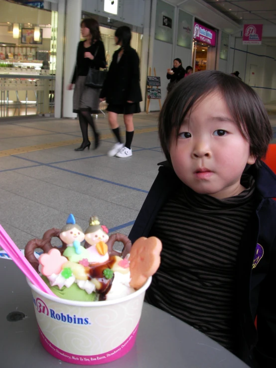 the small child is holding a plastic cup with marshmallows