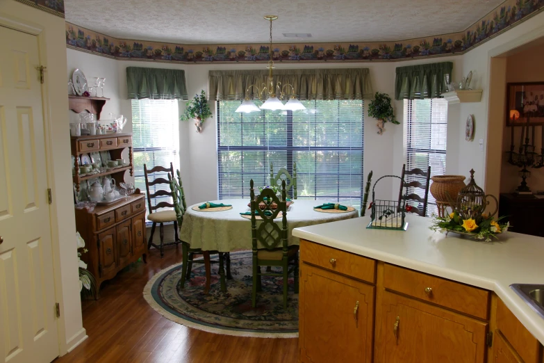 the kitchen has a white counter with chairs and a table