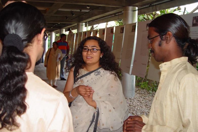 three people wearing traditional attire talking and looking at each other