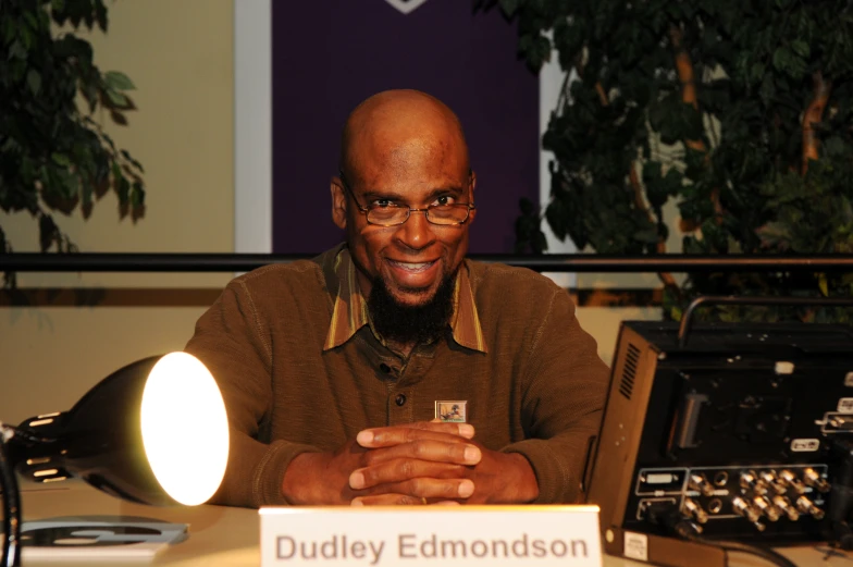 the man is sitting at the desk in front of the radio