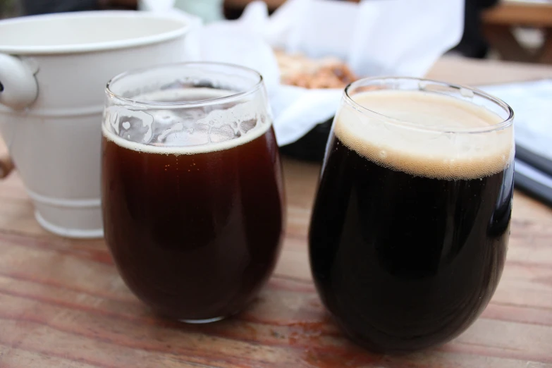 two glasses filled with liquid sitting on top of a wooden table