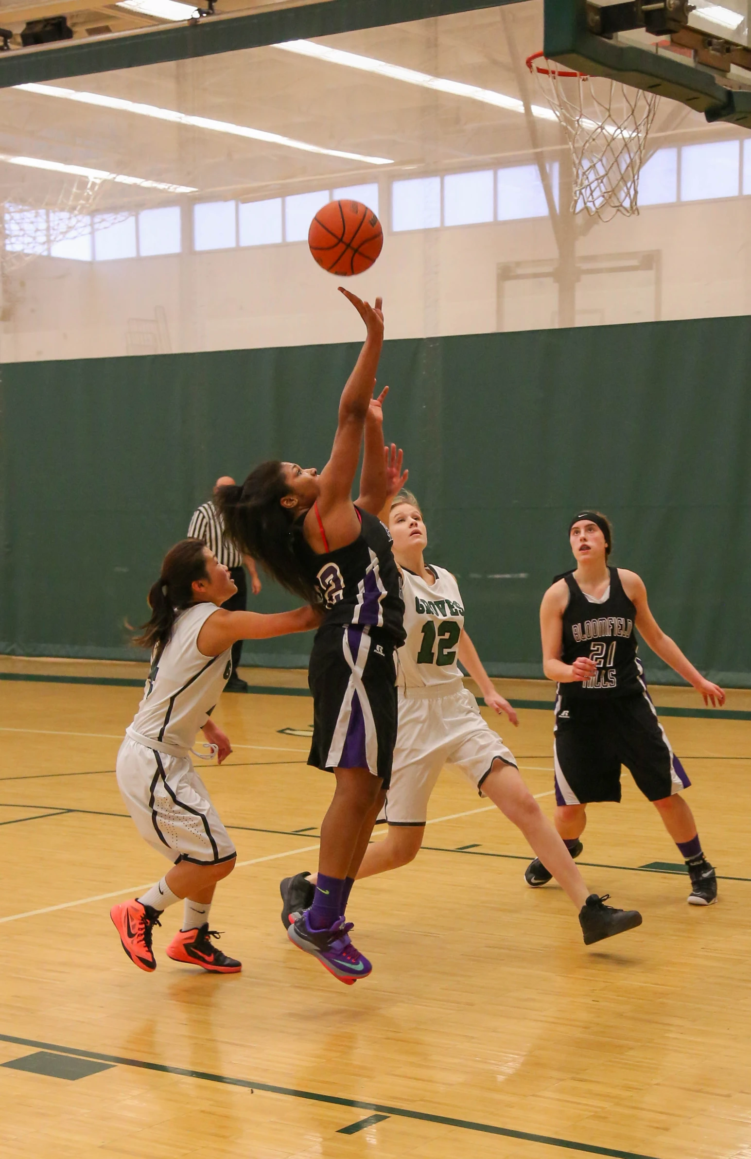 girls are playing a game of basketball in a gym