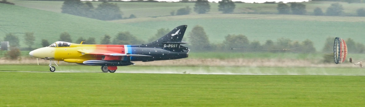 colorful plane on grass runway with a hill in the background