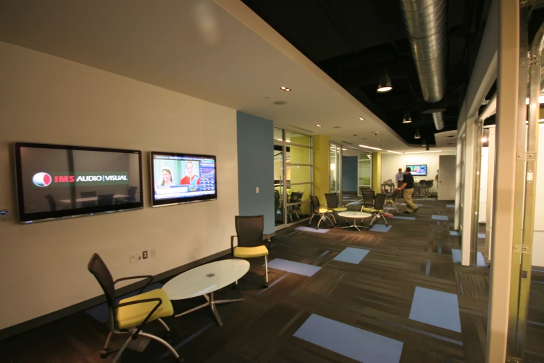 a conference room with chairs, tables and televisions