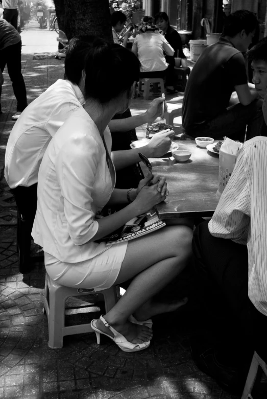 several people sitting at tables in a park having coffee