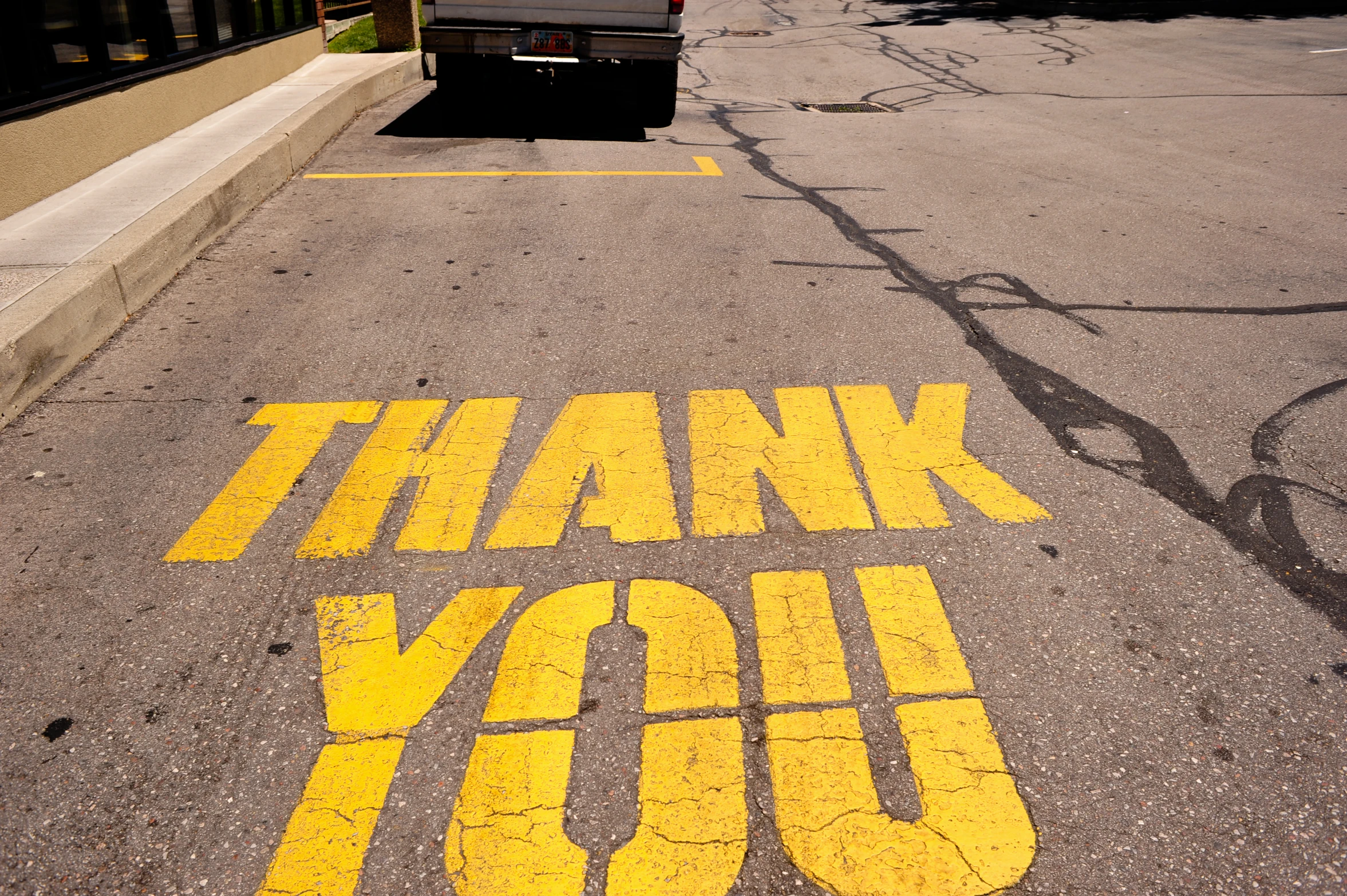 a thank you sign painted on the road in a parking lot