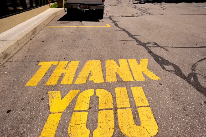 a thank you sign painted on the road in a parking lot