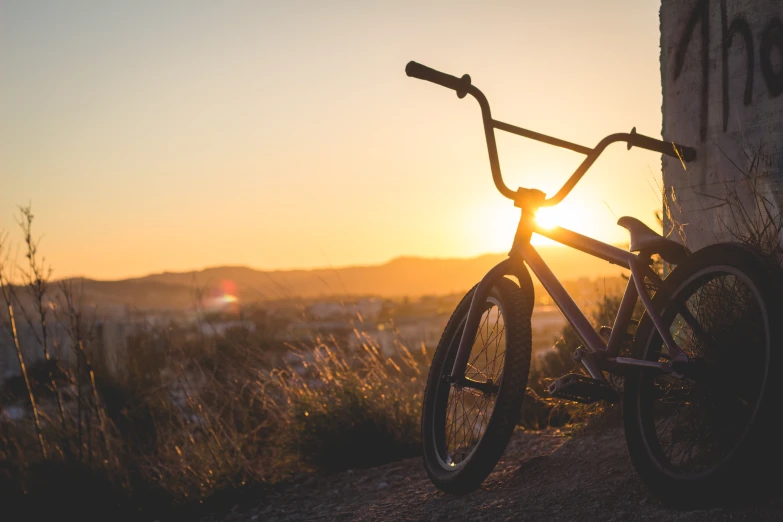 bicycle leaning against wall with sun setting