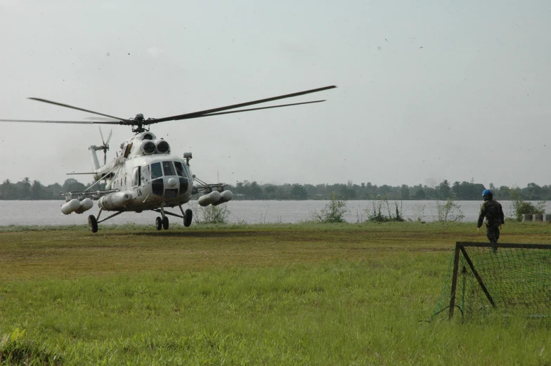 the helicopter is next to the lake with two people