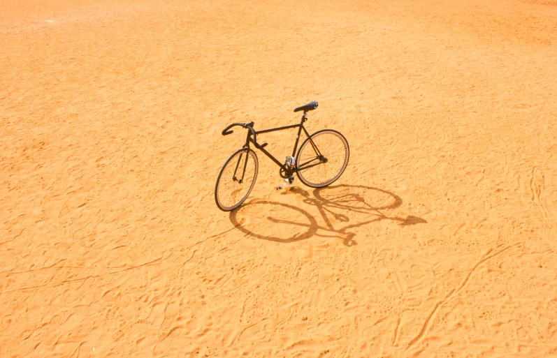 a bicycle sitting on a beach surrounded by sand