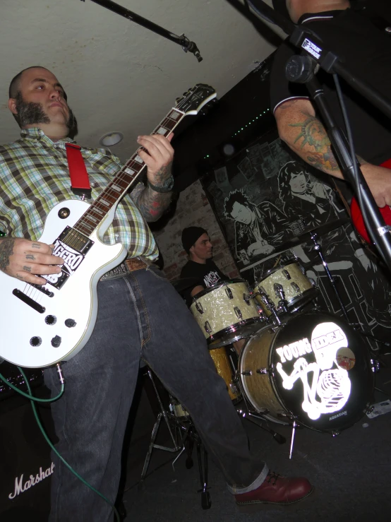 two men with their guitars playing music while wearing matching shirts