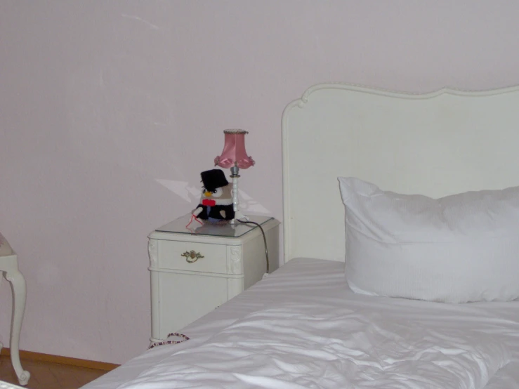 a stuffed toy doll stands on top of a bed