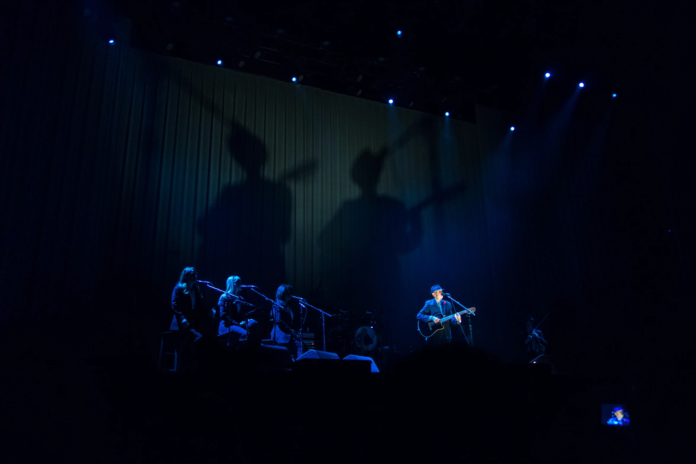 three people standing on stage and shadows on the wall