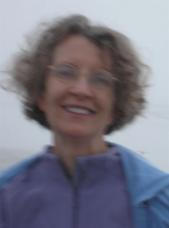 a smiling woman wearing glasses with a red frisbee in front