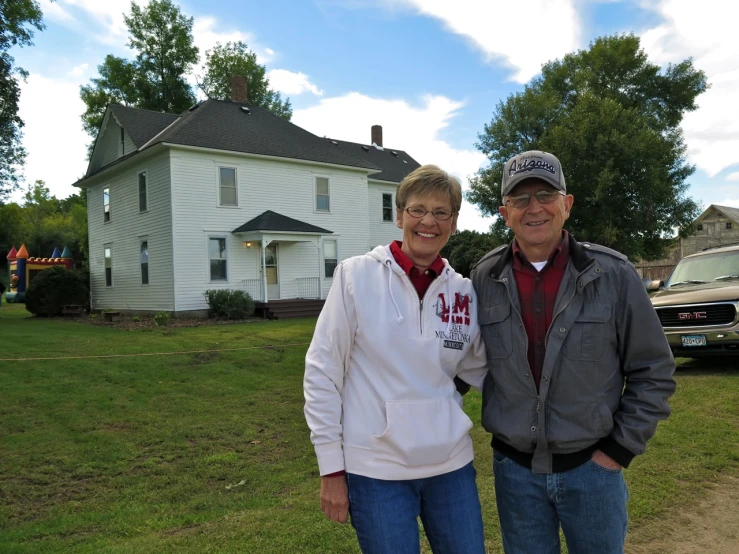 an older couple poses for a po in front of a white house