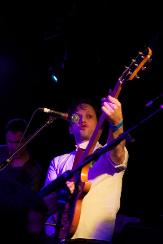 a man with a guitar standing in front of a microphone