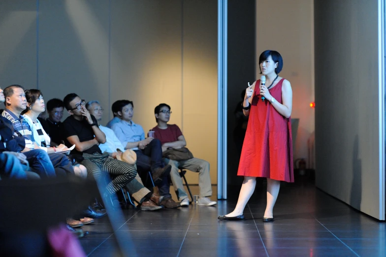 a woman speaking on stage while a crowd looks on