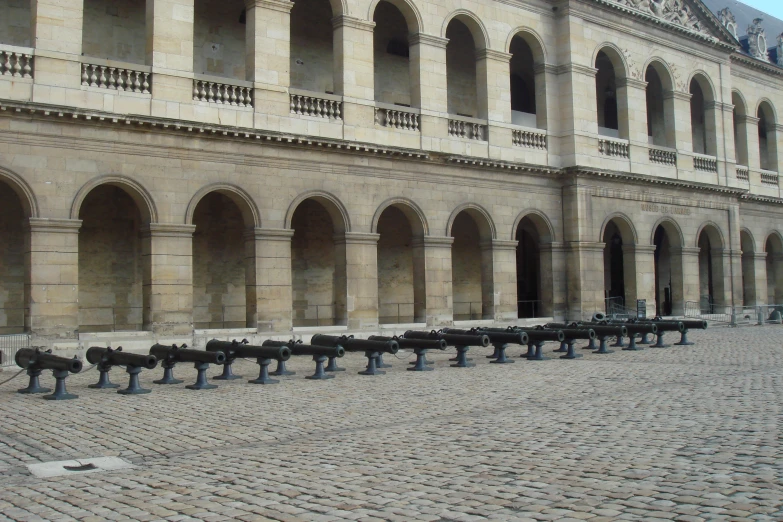 long line of black vases on brick walkway next to building