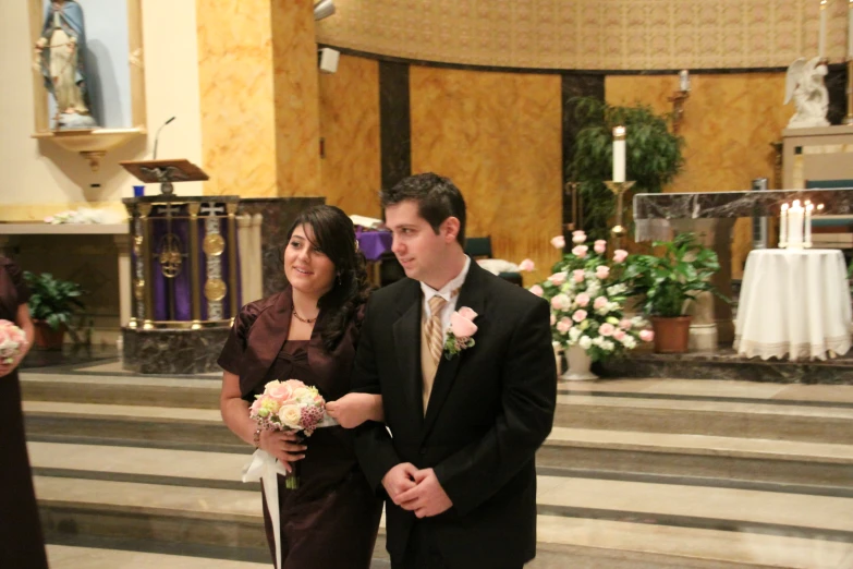 a young couple holding a bouquet in a church