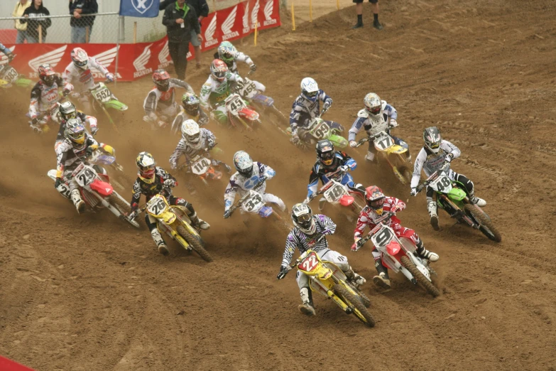 many people racing dirt bikes through a dusty track