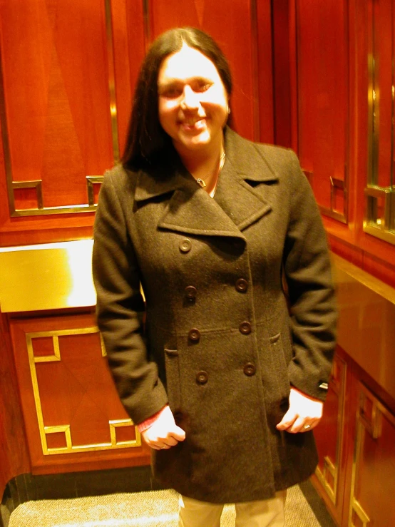 the woman is standing in front of brown cabinets