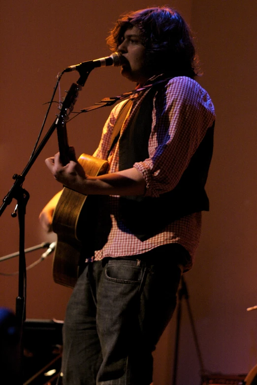 a man with a guitar standing in front of a microphone
