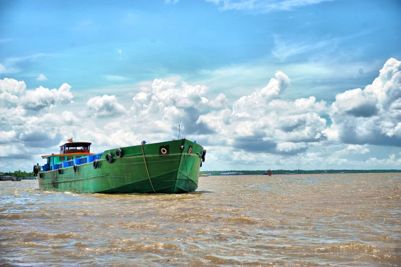 a large green ship sailing across a lake next to a dock