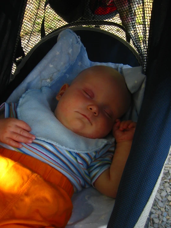 a small baby in an orange and blue sleeping in a crib