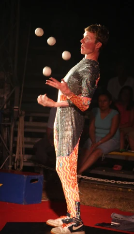 man juggling with two white balls as he stands on the floor