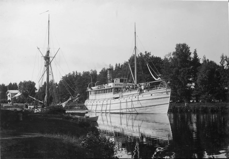 a very tall boat docked at the side of a lake