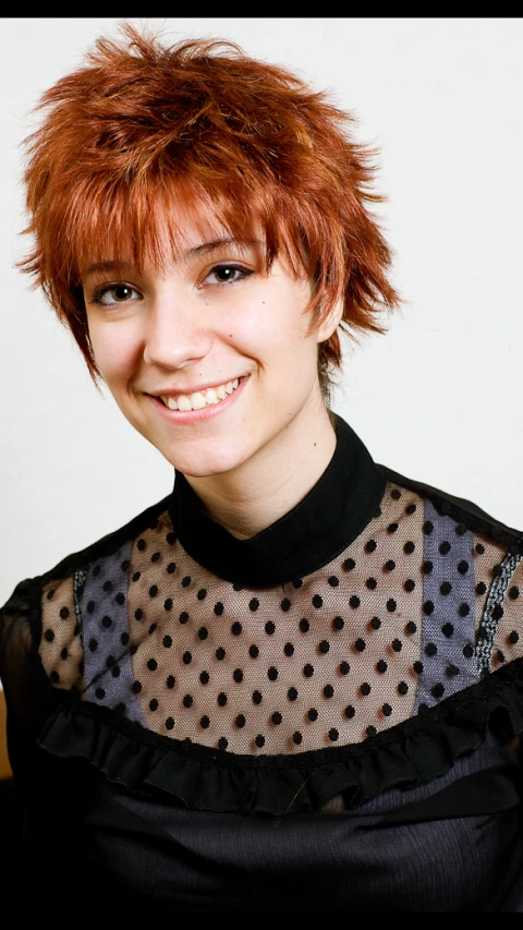 a woman with red hair and short fringe smiles for the camera