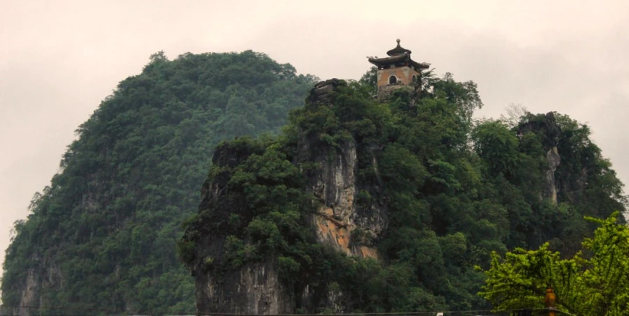 the top of a hill is surrounded by lush trees