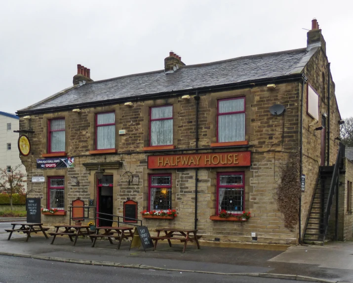 a small brick building with tables sitting outside of it