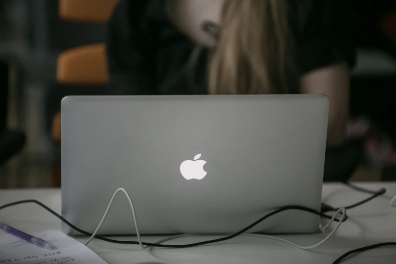 a woman sitting in front of an apple laptop computer