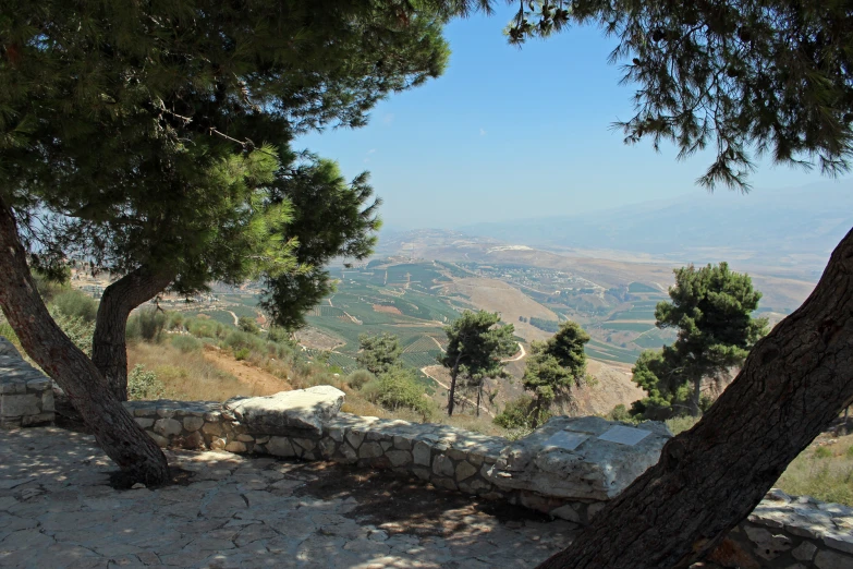 a stone bench with a view of mountains and valley behind it