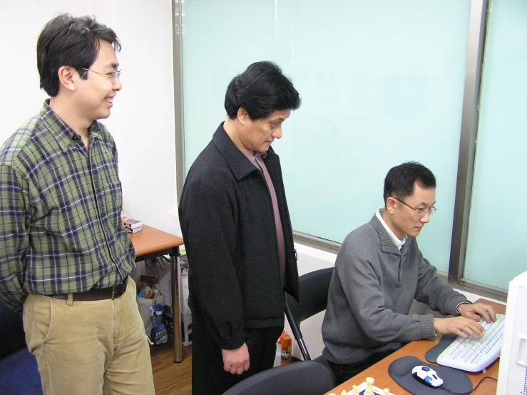 two men looking at a laptop in an office