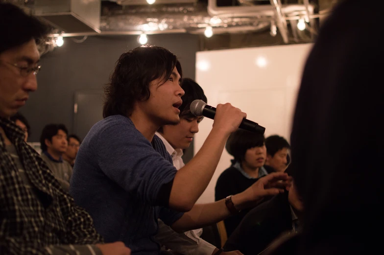 young men singing into a microphone in a recording studio