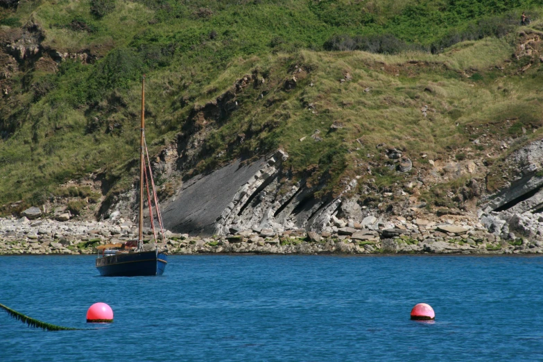 a yacht in the ocean next to a rocky coast